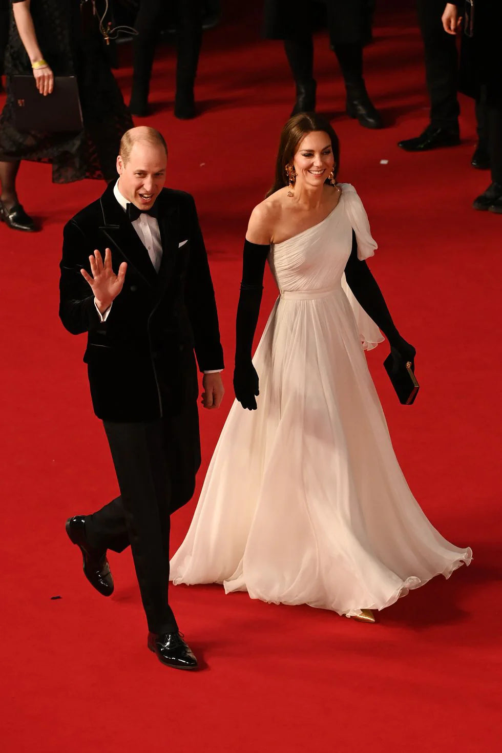Man in formal attire and woman in a white dress on a red carpet