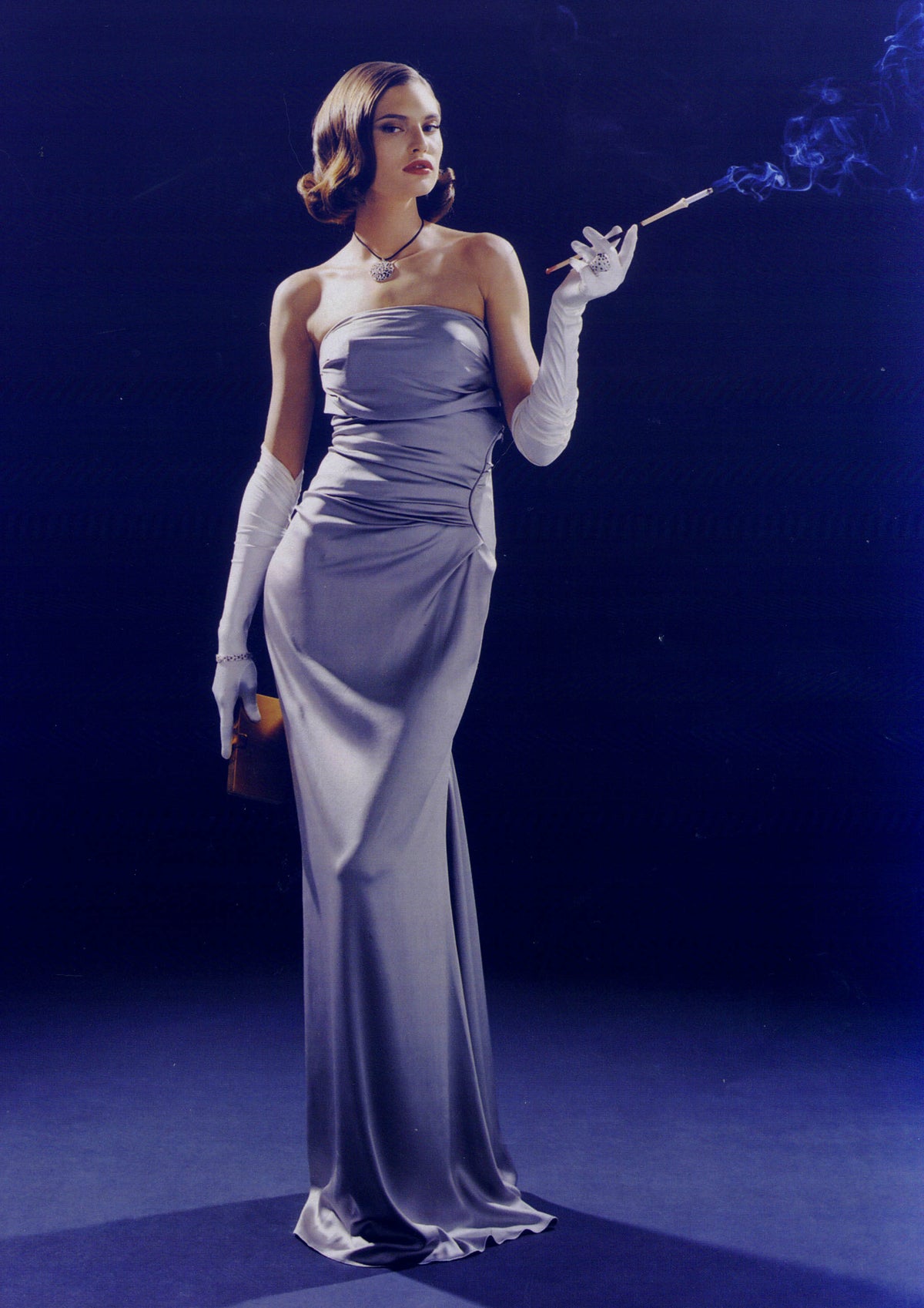 Woman in a long, elegant dress with white gloves against a dark blue background