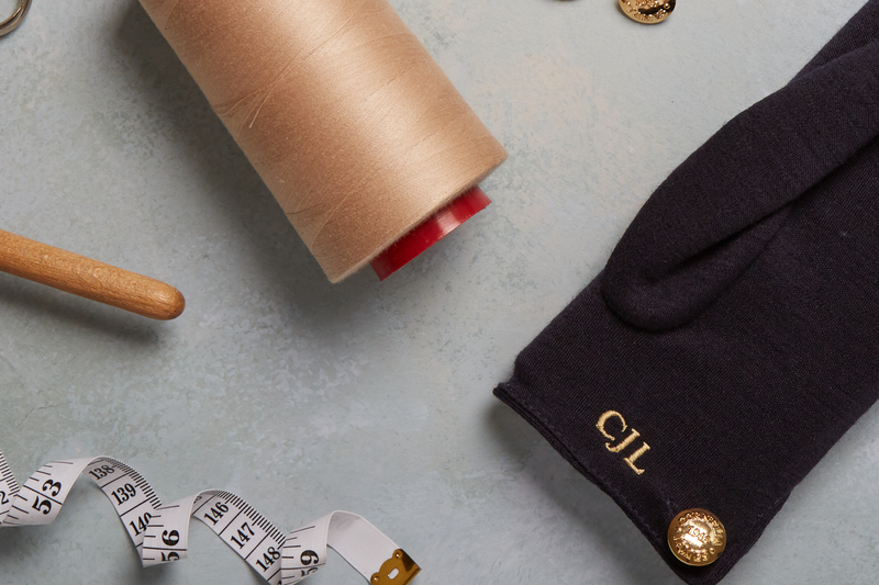 Measuring tape, wooden rolling pin, brown paper roll, and black gloves on a light gray surface.